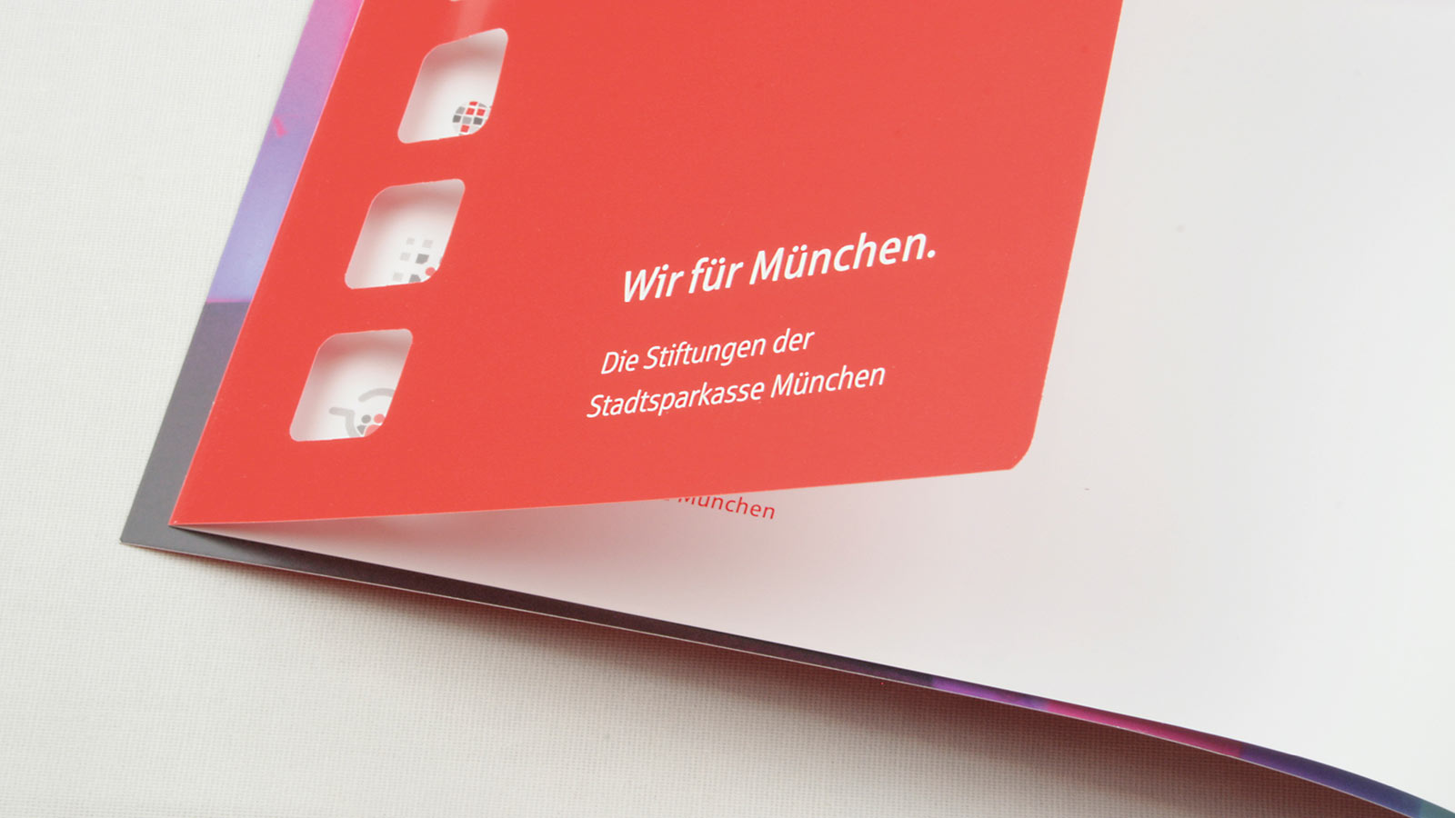 Papierstanzung mit Durchblick auf Folgeseite einer Broschüre der Stadtsparkasse München